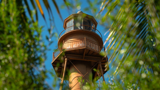 The Sanibel Lighthouse framed by palm fronds under a blue sky on Sanibel Island