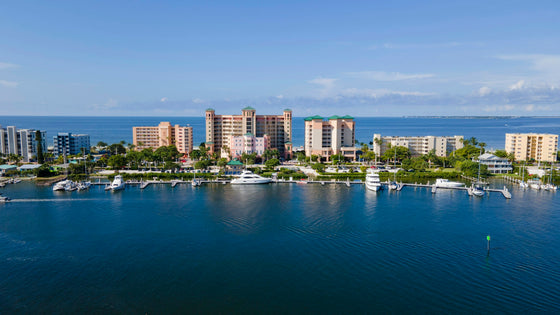 Fort Myers Beach waterfront on a clear day: blue bay and boat docks in front of beachfront buildings and palm trees