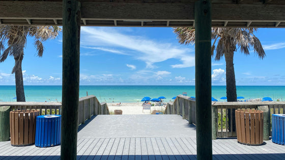Boardwalk opening onto Englewood Beach in Charlotte County, with palm trees, blue umbrellas and turquoise Gulf water