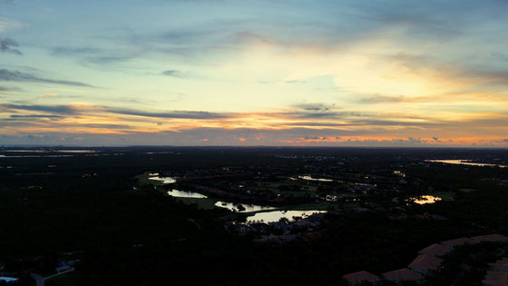 Aerial view over Estero at sunset, with lakes and neighborhoods under a golden sky